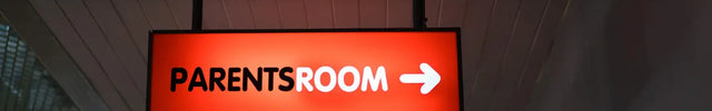 Ceiling-mounted red lit shape lightbox sign with white text and arrow indicating parents room direction
