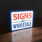 On Rectangular lit-shape lightbox sign displaying the text 'SIGNS AT WHOLESALE' in bold red and blue on a solid royal blue background, shown as a color swatch mockup