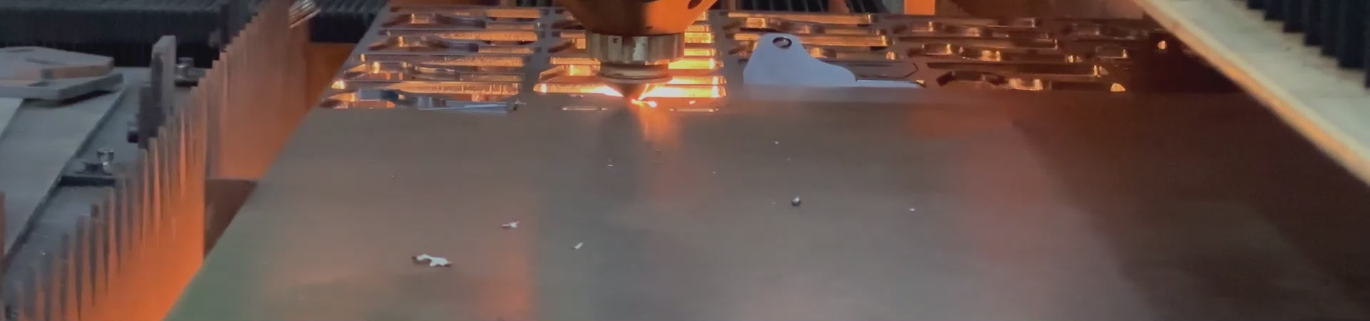 Laser cutting machine cutting metal sheet with sparks at industrial fabrication workshop